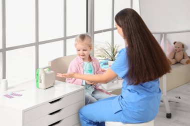 Nebulizörlü kadın çocuk doktoru ve klinikte küçük bir kız.