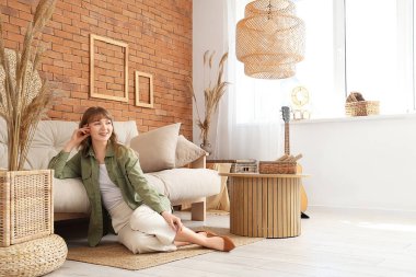 Genç ve güzel bir kadın oturma odasındaki kanepenin yanında dinleniyor.