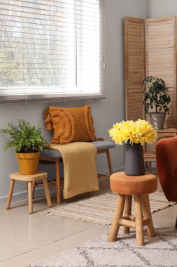 Oturma odasının iç tarafında ekose ve narsist çiçekleri olan rahat bir kanepe.