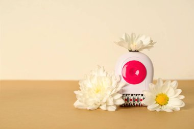 Bej masadaki çiçekli modern epilator.