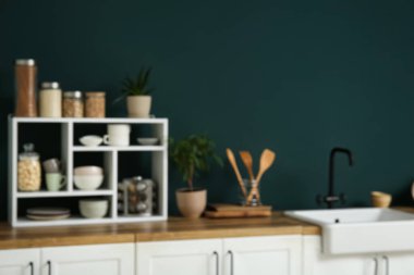 Beyaz tezgahlı, lavabolu ve yeşil duvarlı modern mutfağın bulanık görüntüsü