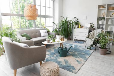 Kanepe, bahçe aletleri ve bitkilerle aydınlık oturma odasının içinde.