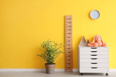 Çocuk odasındaki sarı duvarın yanında ahşap stadyumu olan oyuncaklar tuvalette.