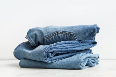 Beyaz arka planda farklı şık kot pantolon yığını