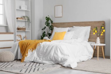 Küçük yatak odasının içinde raf ünitesi, ağaç dalları ve vazoda limonlar var.