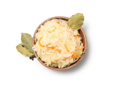 Beyaz arka planda defne yaprakları olan bir kase lezzetli mayalanmış lahana. Üst görünüm