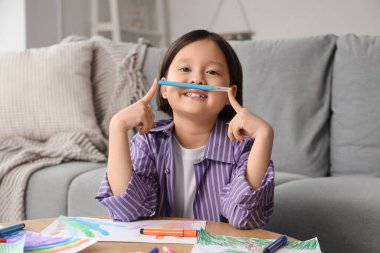 Evdeki masada güzel bir Asyalı kız çiziyor.