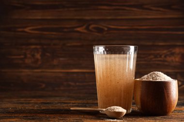 Tahta zemin üzerinde psyllium kabuğu olan bir bardak su.