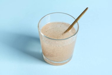 Açık mavi zemin üzerinde psyllium kabuğu olan bir bardak su.