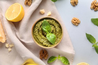 Beyaz arka planda ceviz, peynir ve fesleğen yapraklı bir kase lezzetli pesto sosu