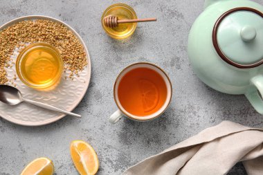 Bir fincan sıcak karabuğday çayı, limonlu ve bal dolu grunge arkaplanda.