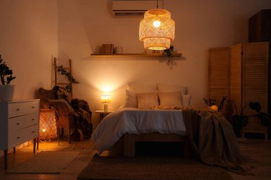 Yatak odasının içinde bej ekose kumaşlar, koltuklar ve geceleri parlayan lambalar.