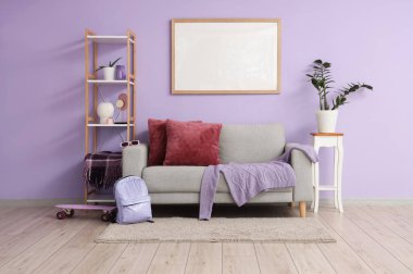 Şık bir kanepe, dekorlu raflar, çiçekli ve duvarda boş bir poster.