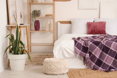 Yatağında raf ünitesi, ev bitkileri ve mor battaniye olan modern yatak odası.