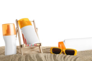 Güneş gözlüğü, dekoratif iskemle ve beyaz arka planda kumdaki güneş kremi şişeleri, yakın plan.