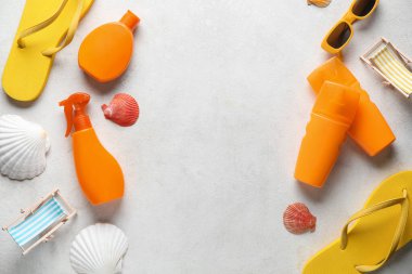 Plaj aksesuarlarından, güneş kremi şişelerinden ve beyaz grunge arka planda deniz kabuklarından yapılmış çerçeve.