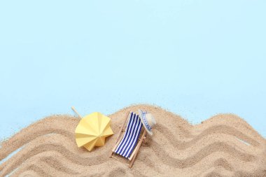 Kumlu yaz kompozisyonu, dekoratif iskemle, mavi arka planda şapka ve şemsiye.