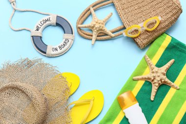 Deniz yıldızlarından yapılmış çerçeve, güneş kremi şişesi ve mavi arka planda plaj aksesuarları.