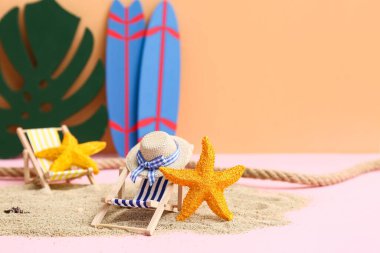 Kum, deniz yıldızı, dekoratif şapka ve arka planda iskemle.