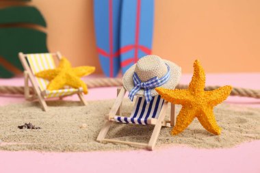 Kum, deniz yıldızı, dekoratif şapka ve arka planda iskemle.