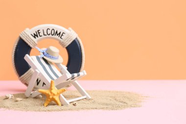 Kum, denizyıldızı, dekoratif yaşam şamandırası, şapka ve şezlong renk arka planda.