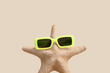 Bej arka planda güneş gözlüklü denizyıldızı
