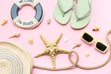 Deniz kabukları, denizyıldızı, halat ve pembe arka planda plaj aksesuarları.
