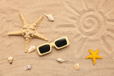 Arka planda deniz kabukları, deniz yıldızları ve kumdaki güneş gözlükleriyle kompozisyon