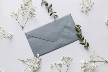 Beyaz arka planda gri zarf ve güzel çingene çiçekleri.