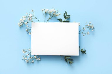 Güzel çingene çiçekleri ve mavi arka planda boş kağıt kağıtları olan kompozisyon