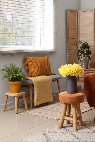 Oturma odasının iç tarafında ekose ve narsist çiçekleri olan rahat bir kanepe.