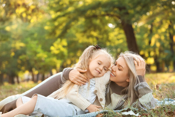 Little girl with her mother lying in park on autumn day