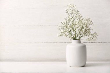 Beyaz ahşap arka planda güzel çingene çiçekleri olan vazo.