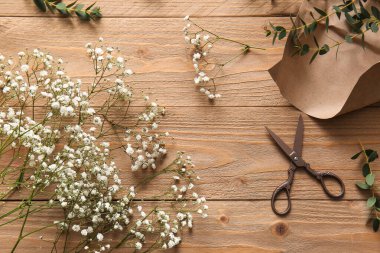 Ahşap zemin üzerinde güzel çigila çiçekleri, makas ve kağıt kompozisyonu