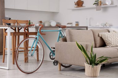 Aydınlık oturma odasındaki kanepenin yanında şık bir bisiklet, yakın plan.