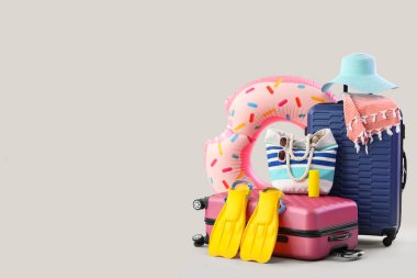 Bavullar, şişme yüzük ve beyaz arka planda plaj aksesuarları.