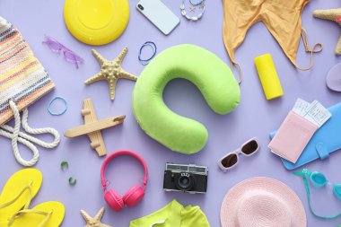 Leylak arka planında fotoğraf makinesi, cep telefonu ve plaj aksesuarları olan kompozisyon