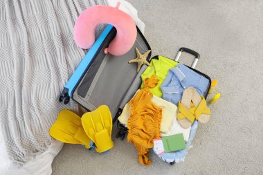 Giysileri ve plaj aksesuarlarıyla dolu bavullar odada, yakın plan.