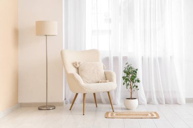 Beyaz koltuklu, lambalı ve büyük pencereli aydınlık oturma odasının içinde.