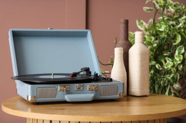 Plak çalar ve dekoratif şişeler odadaki kahverengi duvarın yanındaki masada, yakın plan.