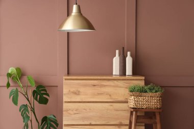 Çekmeceler, dışkılar ve bitkiler odanın içindeki kahverengi duvarın yanında, yakın plan.