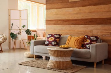 Oturma odasının içi. Kanepesi ve ahşap duvarın yanındaki masa.