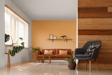 Deri kahverengi kanepe, masa ve koltuk şık bir oturma odasının içinde.