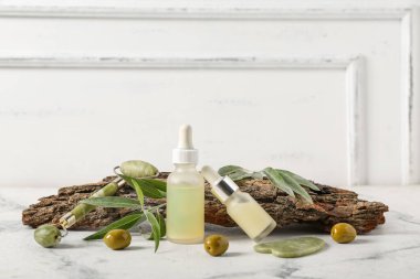 Beyaz duvarın yanındaki mermer masada gerekli zeytinyağı, ağaç kabuğu ve yüz masajı aletleri var.