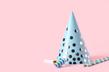 Parti şapkası, pipetler ve pembe arka planda ıslıklar, yakın plan.