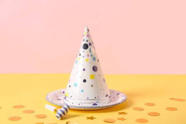 Parti şapkalı kompozisyon, düdük ve kağıt tabak pembe duvarın yanında, yakın plan.