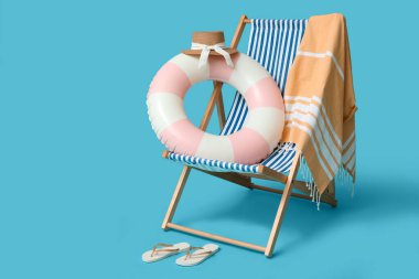 Şişirilebilir yüzük, güverte sandalyesi ve mavi arka planda plaj aksesuarları, yakın plan.