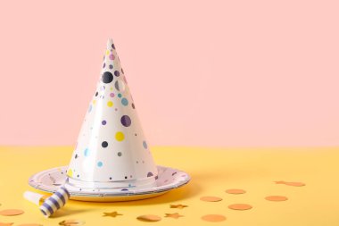 Parti şapkalı kompozisyon, düdük ve kağıt tabak pembe duvarın yanında, yakın plan.