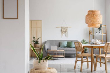 Rahat gri koltuklu, çiçekli ve dizüstü bilgisayarlı bir oturma odası.