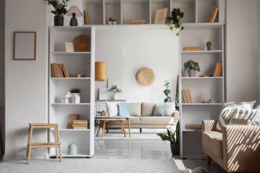 Rahat kanepeleri, merdiveni ve raf üniteleri olan oturma odasının içinde.